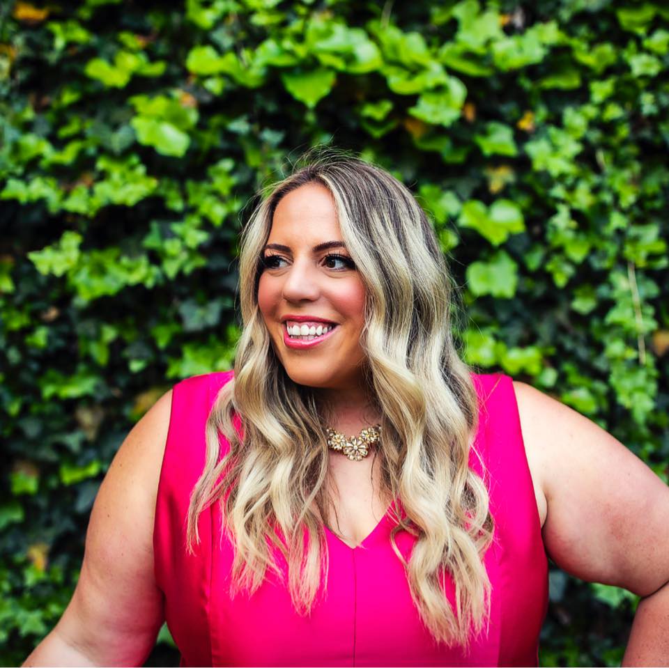 girl in pink dress smiling in front of ivy wall