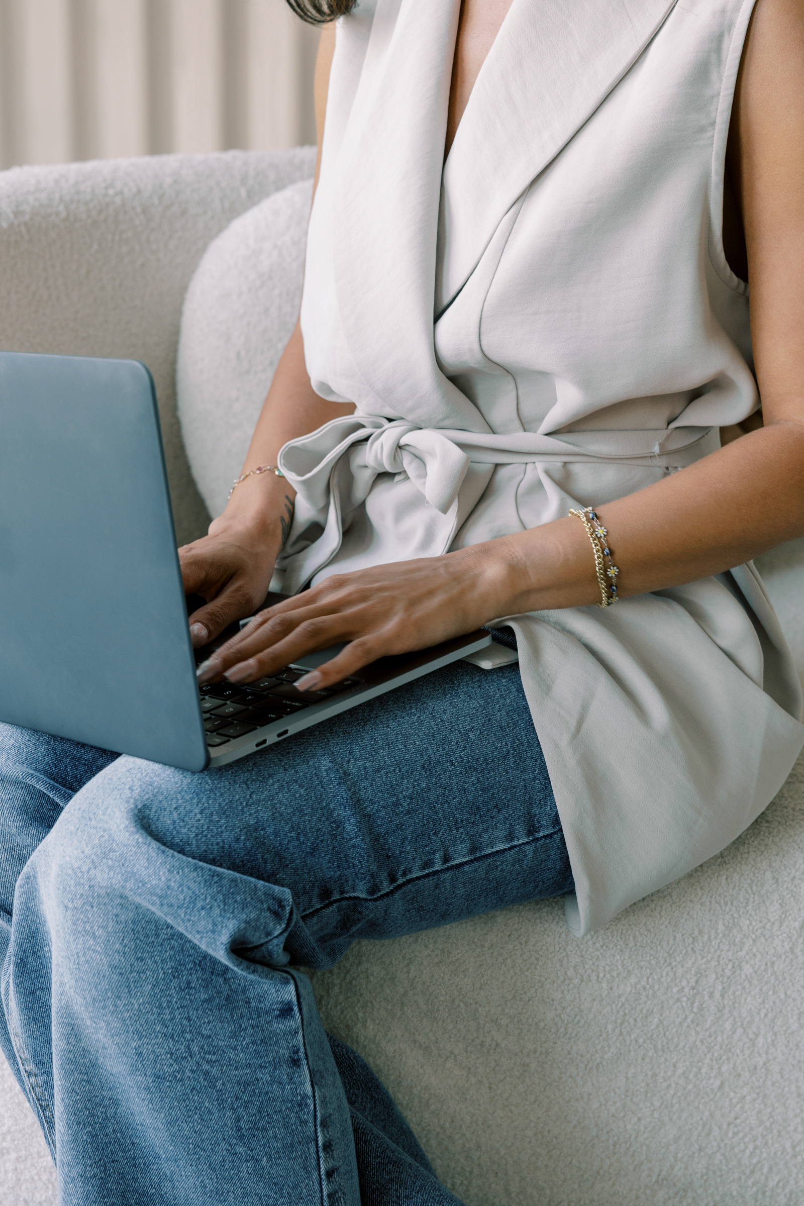 a woman in a light gray wrap top typing on a green laptop